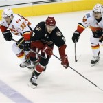 Phoenix Coyotes defender Keith Yandle works the puck between Calgary Flames center Mike Cammalleri, left, and center Jiri Hudler during the second period of an NHL hockey game, Tuesday, Jan. 7, 2014, in Glendale, Ariz. (AP Photo/The Arizona Republic, Michael Chow)