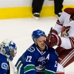 Phoenix Coyotes' Lauri Korpikoski, right, of Finland, checks Vancouver Canucks' Daniel Sedin, centre, of Sweden, as goalie Roberto Luongo looks on during second period NHL hockey game in Vancouver, British Columbia, on Sunday, Jan. 26, 2014. (AP Photo/The Canadian Press, Darryl Dyck)