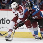Colorado Avalanche center Nathan MacKinnon (29) reaches for the puck against Phoenix Coyotes center Kyle Chipchura (24) during the first period of an NHL hockey game in Denver on Tuesday, Dec. 10, 2013. (AP Photo/Joe Mahoney)
