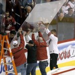 Jobing.com Arena workers install a new piece of board glass after a section broke during the third period of an NHL hockey game between the Phoenix Coyotes and the Calgary Flames, Tuesday, Jan. 7, 2014, in Glendale, Ariz. The Coyotes defeated the Flames 6-0. (AP Photo/Ross D. Franklin)