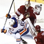 Phoenix Coyotes' Chad Johnson, top, deflects the puck as he makes a save as Edmonton Oilers' Sam Gagner (89) tries to get out of the way as Coyotes' Keith Yandle (3) looks on during the second period in an NHL hockey game Wednesday, Jan. 30, 2013, in Glendale, Ariz.(AP Photo/Ross D. Franklin)