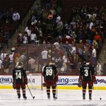 Phoenix Coyotes' Antoine Vermette (50), Chris Conner (14), Mikkel Boedker (89), of Denmark, Keith Yandle (3), and Derek Morris (53) stand along with the crowd for a moment of silence for the victims of the bombing at the Boston Marathon prior to an NHL hockey game between the San Jose Sharks and the Coyotes, on Monday, April 15, 2013 in Glendale, Ariz. (AP Photo/Ross D. Franklin)