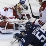 Phoenix Coyotes' goaltender Mike Smith (41) tries to cover a loose puck with Winnipeg Jets' Mark Scheifele (55) and Coyotes' David Schlemko (6) in front of the net during third period NHL hockey action in Winnipeg, Canada, Monday, Jan. 13, 2014. (AP Photo/The Canadian Press, Trevor Hagan)