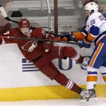 New York Islanders' Cal Clutterbuck (15) checks Phoenix Coyotes' Oliver Ekman-Larsson, of Sweden, into the boards during the third period of an NHL hockey game Thursday, Dec. 12, 2013, in Glendale, Ariz. The Coyotes defeated the Islanders 6-3. (AP Photo/Ross D. Franklin)