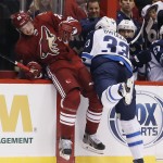 Winnipeg Jets' Dustin Byfuglien (33) checks Arizona Coyotes' Oliver Ekman-Larsson (23), of Sweden, into the boards during the first period of an NHL hockey game Thursday, Oct. 9, 2014, in Glendale, Ariz. (AP Photo/Ross D. Franklin)