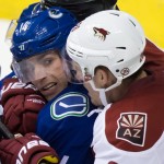 Arizona Coyotes' Michael Stone, right, ties up Vancouver Canucks' Alex Burrows during third period NHL hockey action in Vancouver, British Columbia on Monday, Dec. 22, 2014. (AP Photo/The Canadian Press, Darryl Dyck)