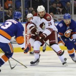 Arizona Coyotes center Kyle Chipchura (24) drives the puck between New York Islanders defenseman Travis Hamonic (3) and center Ryan Strome (18) in the first period of an NHL hockey game Tuesday, Feb. 24, 2015, in Uniondale, N.Y. (AP Photo/Kathy Kmonicek)