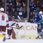 Arizona Coyotes' Sam Gagner (9), goalie Mike Smith, Vancouver Canucks' Alexander Edler, of Sweden, (23) and Zbynek Michalek, of the Czech Republic, (4) look on as a fan celebrates after Canucks' Kevin Bieksa, not seen, scored during first period of an NHL hockey game in Vancouver, British Columbia, Monday, Dec. 22, 2014. (AP Photo/The Canadian Press, Darryl Dyck)