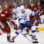 Arizona Coyotes' Keith Yandle (3) flips the puck past Tampa Bay Lightning Tyler Johnson (9) during the first period of an NHL hockey game Saturday, Feb. 21, 2015, in Glendale, Ariz. (AP Photo/Ross D. Franklin)