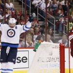 Winnipeg Jets' Blake Wheeler (26) celebrates his goal, the first of two during the first period, against the Arizona Coyotes as Coyotes' Oliver Ekman-Larsson (23), of Sweden, skates in front of the goal area in an NHL hockey game Thursday, Oct. 9, 2014, in Glendale, Ariz. (AP Photo/Ross D. Franklin)