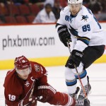 As Arizona Coyotes' Shane Doan (19) falls to the ice he tries to get off a pass as San Jose Sharks' Barclay Goodrow (89) closes in during the first period of an NHL hockey game Tuesday, Jan. 13, 2015, in Glendale, Ariz. (AP Photo/Ross D. Franklin)