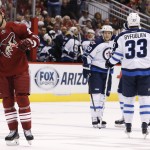 Winnipeg Jets' Dustin Byfuglien (33) and Toby Enstrom (39), of Sweden, celebrate a goal by teammate Blake Wheeler as Arizona Coyotes' David Moss, left, skates dejectedly away during the first period of an NHL hockey game Thursday, Oct. 9, 2014, in Glendale, Ariz. (AP Photo/Ross D. Franklin)