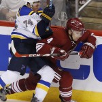 St. Louis Blues' T.J. Oshie (74) checks Arizona Coyotes' Zbynek Michalek (4), of the Czech Republic, into the boards during the third period of an NHL hockey game Saturday, Oct. 18, 2014, in Glendale, Ariz. The Blues defeated the Coyotes 6-1. (AP Photo/Ross D. Franklin)