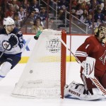 Phoenix Coyotes' Thomas Greiss (1), of Germany, gives up a goal to Winnipeg Jets' Andrew Ladd as Jets' Michael Frolik (67), of the Czech Republic, skates behind the net during the first period of an NHL hockey game, Tuesday, April 1, 2014, in Glendale, Ariz. (AP Photo/Ross D. Franklin)