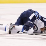 Winnipeg Jets' Evander Kane grabs for his injured right knee as he stays on the ice during the first period of an NHL hockey game against the Arizona Coyotes Thursday, Oct. 9, 2014, in Glendale, Ariz. (AP Photo/Ross D. Franklin)