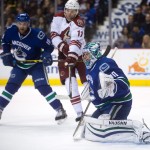 Vancouver Canucks goalie Ryan Miller, right, watches the puck as Arizona Coyotes' Martin Hanzal, of the Czech Republic, (11) tries to redirect it and Canucks' Ryan Stanton defends during first period of an NHL hockey game in Vancouver, British Columbia, Monday, Dec. 22, 2014. (AP Photo/The Canadian Press, Darryl Dyck)