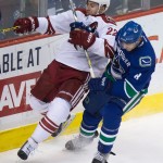 Vancouver Canucks' Chris Tanev, right, checks Arizona Coyotes' Brandon McMillan during second period NHL hockey action in Vancouver, British Columbia on Monday, Dec. 22, 2014. (AP Photo/The Canadian Press, Darryl Dyck)