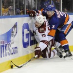 Arizona Coyotes right wing Shane Doan (19) and New York Islanders defenseman Travis Hamonic (3) battle for the puck against the boards in the third period of an NHL hockey game at Nassau Coliseum on Tuesday, Feb. 24, 2015, in Uniondale, N.Y. The Islanders won 5-1. (AP Photo/Kathy Kmonicek)