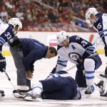 As a Winnipeg Jets training staff member checks on injured Evander Kane, teammates Dustin Byfuglien (33), Blake Wheeler (26) and Mark Scheifele (55) look on during the first period of an NHL hockey game against the Arizona Coyotes Thursday, Oct. 9, 2014, in Glendale, Ariz. (AP Photo/Ross D. Franklin)
