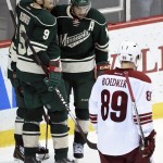 Arizona Coyotes left wing Mikkel Boedker (89), of Denmark, skates past as Minnesota Wild center Mikko Koivu (9) and right wing Jason Pominville (29) congratulate left wing Zach Parise (11) on an empty-net goal during the third period of an NHL hockey game Saturday, Jan. 17, 2015, in St. Paul, Minn. The Wild won 3-1. (AP Photo/Hannah Foslien)
