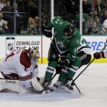 Arizona Coyotes goalie Mike Smith (41) attempts to get control of a loose puck under pressure from Dallas Stars' Jamie Benn (14) as Coyotes' Brandon McMillan (22) helps on the play in the first period of an NHL hockey game, Thursday, Nov. 20, 2014, in Dallas. (AP Photo/Tony Gutierrez)