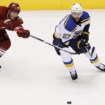 St. Louis Blues' Alex Pietrangelo (27) gets the puck slapped away by Arizona Coyotes' Mikkel Boedker (89), of Denmark, during the first period of an NHL hockey game Saturday, Oct. 18, 2014, in Glendale, Ariz. (AP Photo/Ross D. Franklin)