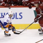Arizona Coyotes' Shane Doan (19) sends the puck off the helmet of New York Islanders' Brian Strait (37) during the second period of an NHL hockey game Saturday, Nov. 8, 2014, in Glendale, Ariz. The Islanders defeated Coyotes 1-0. (AP Photo/Ross D. Franklin)