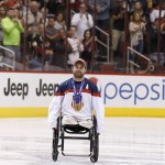 Josh Sweeney, U.S. sled hockey team member for the Paralympic Games, gets a standing ovation from the crowd as he is introduced before an NHL hockey game between the Phoenix Coyotes and the Minnesota Wild, Saturday, March 29, 2014, in Glendale, Ariz. Sweeney a former Marine sergeant, scored a breakaway goal as the United State defeated Russia 1-0 to win the gold medal earlier this month. (AP Photo/Ross D. Franklin)