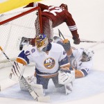 New York Islanders' Jaroslav Halak (41) makes a save on a shot as Arizona Coyotes' Brandon McMillan (22) is hit by Islanders' Frans Nielsen, right, during the second period of an NHL hockey game Saturday, Nov. 8, 2014, in Glendale, Ariz. The Islanders defeated Coyotes 1-0. (AP Photo/Ross D. Franklin)