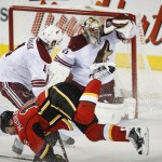 Arizona Coyotes' Zbynek Michalek, left, from the Czech Republic, upends Calgary Flames' Brian McGrattan in front of goalie Mike Smith during the second period of an NHL hockey game Thursday, Nov. 13, 2014, in Calgary, Alberta. (AP Photo/The Canadian Press, Jeff McIntosh)