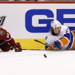 New York Islanders' Matt Martin (17) gets a pass off after being upended by Arizona Coyotes' Joe Vitale (14) during the first period of an NHL hockey game Saturday, Nov. 8, 2014, in Glendale, Ariz. (AP Photo/Ross D. Franklin)