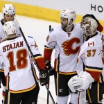 Calgary Flames goalie Joni Ortio (37), of Finland, celebrates the Flames' 4-1 win over the Arizona Coyotes with teammates Matt Stajan (18), Dennis Wideman (6) and Brandon Bollig after an NHL hockey game Thursday, Jan. 15, 2015, in Glendale, Ariz. (AP Photo/Ross D. Franklin)