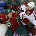 Minnesota Wild's Jared Spurgeon, left, keeps Arizona Coyotes' Brandon McMillan away from a chase for the puck during the third of an NHL hockey game, Thursday, Oct. 23, 2014, in St. Paul, Minn. The Wild won 2-0. (AP Photo/Jim Mone)
