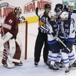 Arizona Coyotes' Mike Smith (41) dejectedly stands in front of the net as Winnipeg Jets' Dustin Byfuglien (33) celebrates his goal with teammates Jim Slater (19), Blake Wheeler (26) and Paul Postma (4) as referee Dan O'Rourke (9) keeps the players away from the goalie during the second period of an NHL hockey game Thursday, Oct. 9, 2014, in Glendale, Ariz. The Jets defeated the Coyotes 6-2. (AP Photo/Ross D. Franklin)