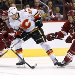 Calgary Flames' David Jones (19) tries to control the puck as Arizona Coyotes' Philip Samuelsson (25) and David Moss (18) arrive to defend during the second period of an NHL hockey game Thursday, Jan. 15, 2015, in Glendale, Ariz. (AP Photo/Ross D. Franklin)