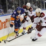 New York Islanders defenseman Lubomir Visnovsky (11) battles for the puck with Arizona Coyotes defenseman Andrew Campbell (45) and right wing David Moss (18) in the first period of an NHL hockey game Tuesday, Feb. 24, 2015, in Uniondale, N.Y. (AP Photo/Kathy Kmonicek)