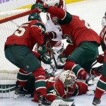 Minnesota Wild goalie Darcy Kuemper sprawls on the ice, bottom, as teammates try to keep Arizona Coyotes' Brandon McMillan, top in white, at bay during the first period of an NHL hockey game, Thursday, Oct. 23, 2014, in St. Paul, Minn. (AP Photo/Jim Mone)
