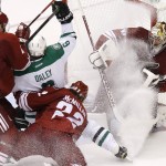 Battling a spray of ice in his face, Arizona Coyotes' Mike Smith, right, makes a save on a shot by Dallas Stars' Trevor Daley (6) as Coyotes' Zbynek Michalek (4), of the Czech Republic, and Brandon McMillan (22) arrives to defend during the second period of an NHL hockey game Tuesday, Nov. 11, 2014, in Glendale, Ariz. (AP Photo/Ross D. Franklin)