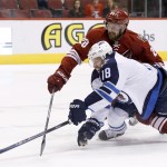 Winnipeg Jets' Bryan Little (18) tries to get a shot off as Phoenix Coyotes' Chris Summers (20) defends during the first period of an NHL hockey game, Tuesday, April 1, 2014, in Glendale, Ariz. (AP Photo/Ross D. Franklin)
