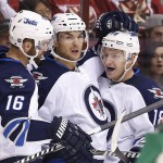 Winnipeg Jets' Bryan Little (18) celebrates his goal against the Arizona Coyotes with teammates Andrew Ladd (16) and Michael Frolik, center, of the Czech Republic, during the first period of an NHL hockey game Thursday, Oct. 9, 2014, in Glendale, Ariz. (AP Photo/Ross D. Franklin)