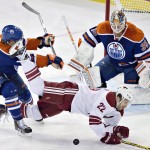 Arizona Coyotes' Brandon McMillan (22) is knocked down by Edmonton Oilers' Taylor Hall (4) as goalie Viktor Fasth (35) looks for the puck during the second period of an NHL hockey game in Edmonton, Alberta, on Monday, Dec. 1, 2014. (AP Photo/The Canadian Press, Jason Franson)