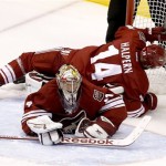 Phoenix Coyotes' Jeff Halpern (14) falls over goalie Mike Smith during the second period in an NHL hockey game against the Minnesota Wild Thursday, Jan. 9, 2014, in Glendale, Ariz. (AP Photo/Ross D. Franklin)