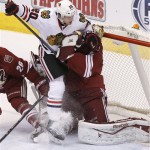 Chicago Blackhawks' Brandon Saad (20) slams into Phoenix Coyotes goalie Mike Smith, right, during the second period in an NHL hockey game, Friday Feb. 7, 2014, in Glendale, Ariz. (AP Photo/Ross D. Franklin)