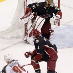 Phoenix Coyotes goalie Mike Smith deflects a shot on goal by Minnesota Wild Pierre-Marc Bouchard (96) as Coyotes' Zbynek Michalek (4) defends during the third period of an NHL hockey game, Monday, Feb. 4, 2013, in Glendale, Ariz. The Coyotes won 2-1. (AP Photo/Matt York)