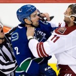 
Linesman Vaughan Rody, left, tries to separate Vancouver Canucks' Dan Hamhuis, center, and Phoenix Coyotes' Martin Hanzal, of the Czech Republic, during the third period of an NHL hockey game in Vancouver, British Columbia, on Sunday, Jan. 26, 2014. (AP Photo/The Canadian Press, Darryl Dyck)