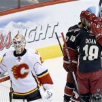Calgary Flames' Reto Berra, left, of Switzerland, looks away as Phoenix Coyotes' Shane Doan (19) celebrates his goal with teammates, including Mikkel Boedker (89), of Denmark, Keith Yandle (3) and Mike Ribeiro (63) during the second period of an NHL hockey game, Tuesday, Jan. 7, 2014, in Glendale, Ariz. (AP Photo/Ross D. Franklin)