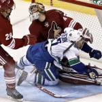 Vancouver Canucks' Daniel Sedin (22), of Sweden, collides with Phoenix Coyotes' Mike Smith as Coyotes' Michael Stone (29) watches during the second period in an NHL hockey game, Thursday, March 21, 2013, in Glendale, Ariz. (AP Photo/Ross D. Franklin)