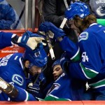 Vancouver Canucks' Ryan Kesler, left, and Kellan Lain, right, help Zack Kassian after he fell into the bench while trying to avoid a too many men penalty on a line change during the second period of an NHL hockey game against the Phoenix Coyotes in Vancouver, British Columbia, on Sunday, Jan. 26, 2014. (AP Photo/The Canadian Press, Darryl Dyck)
