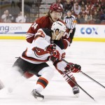  New Jersey Devils' Patrik Elias (26), of the Czech Republic, gets a pass off as he is hit by Phoenix Coyotes' Tim Kennedy (34) during the first period of an NHL hockey game on Saturday, Jan. 18, 2014, in Glendale, Ariz. (AP Photo/Ross D. Franklin)