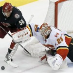 Calgary Flames' Reto Berra (29), of Switzerland, leans out to flip the puck away with his stick before Phoenix Coyotes' Antoine Vermette (50) is able to get to the puck during the second period of an NHL hockey game, Tuesday, Jan. 7, 2014, in Glendale, Ariz. (AP Photo/Ross D. Franklin)